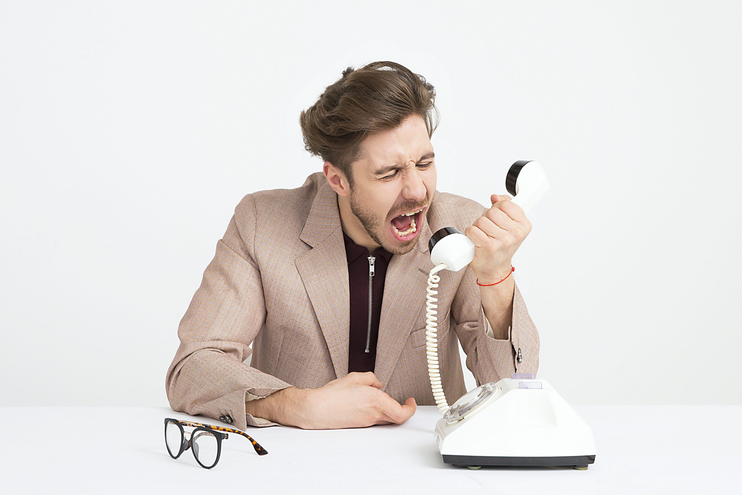 angry man on phone, white background, white phone, eyeglasses on the desk